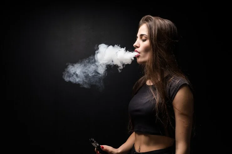 1 young-beautiful-woman-vaping-e-cigarette-black-wall_231208-3631