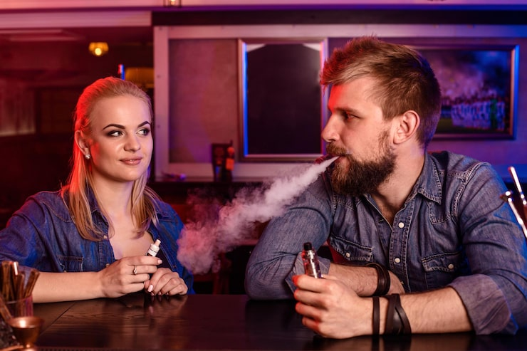 1 a man and a woman vaping in a bar with red and blue lighting, smoke, and a casual atmosphere