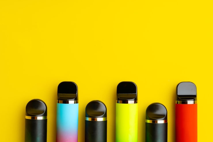 1 several colorful disposable vapes arranged in a row against a bright yellow background